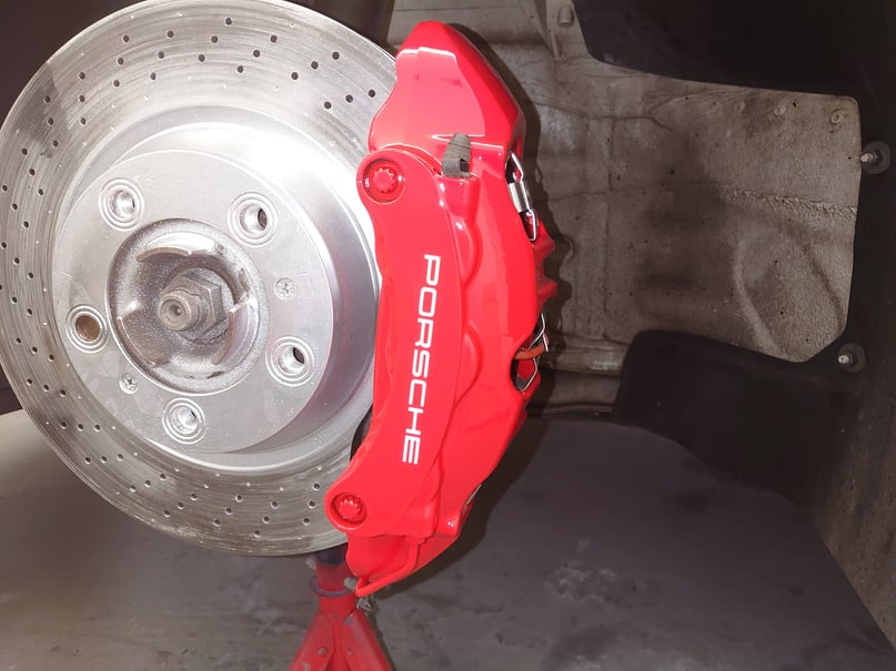 a red brake caliper, silver disc on the front of a porsche car, custom painting in cardiff